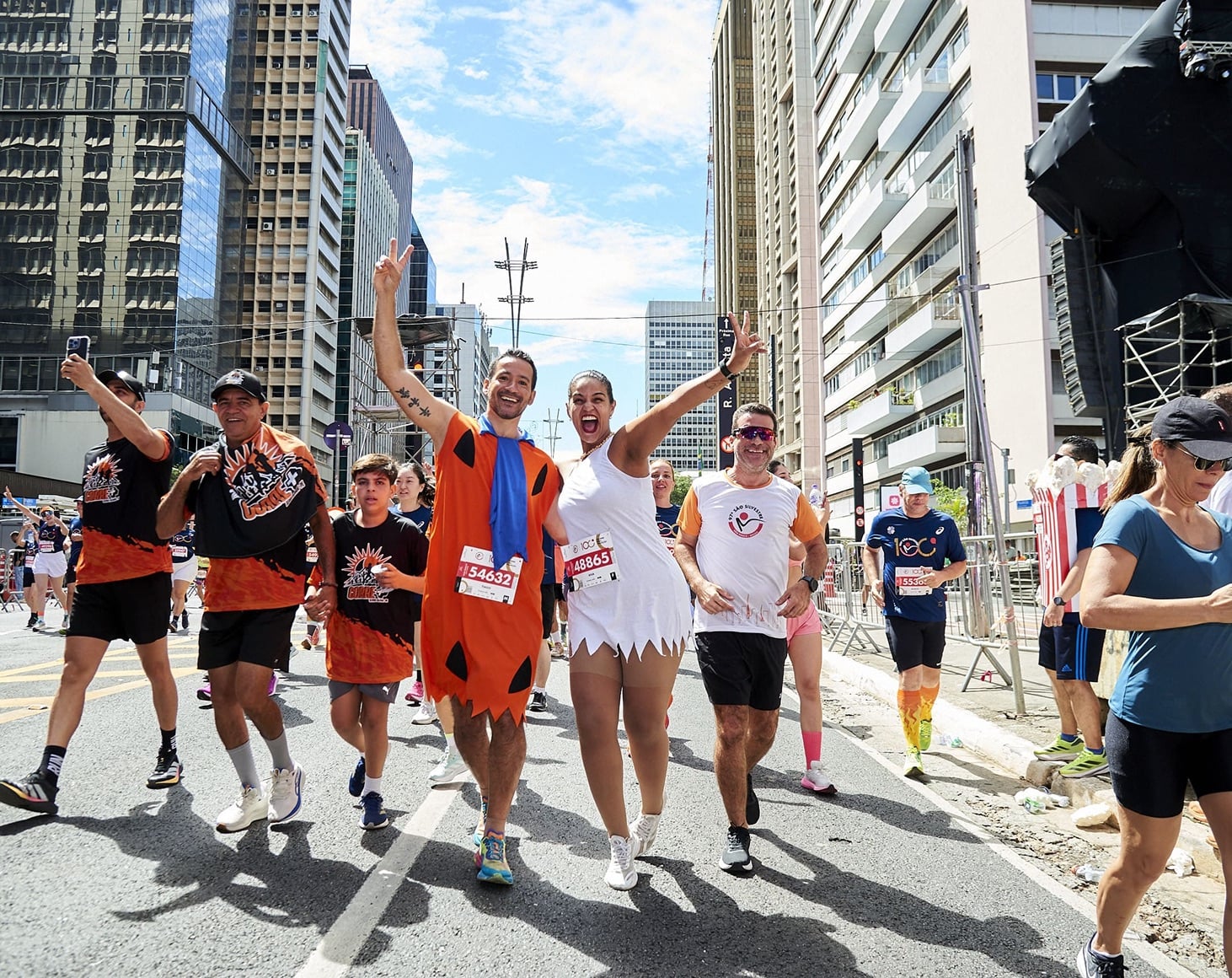 Corredores fantasiados dos Flintstones sorrindo durante a prova